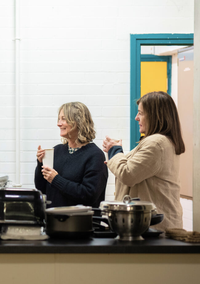 Two women having cups of tea in the kitchen at The Bronte Youth and Community Centre