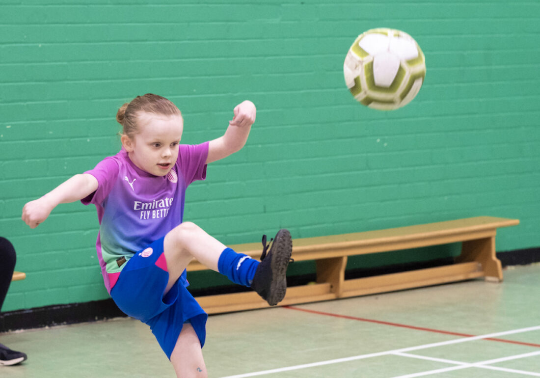 A young member of The Bronte youth club playing football in the sports hall at The Bronte Youth and Community Centre based in Liverpool City Centre