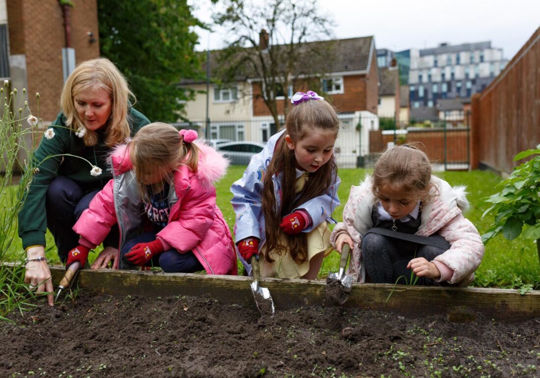 A group of young members of The Bronte Youth and Community Centre learning how to garden with a volunteer in The Bronte garden based in Liverpool City Centre