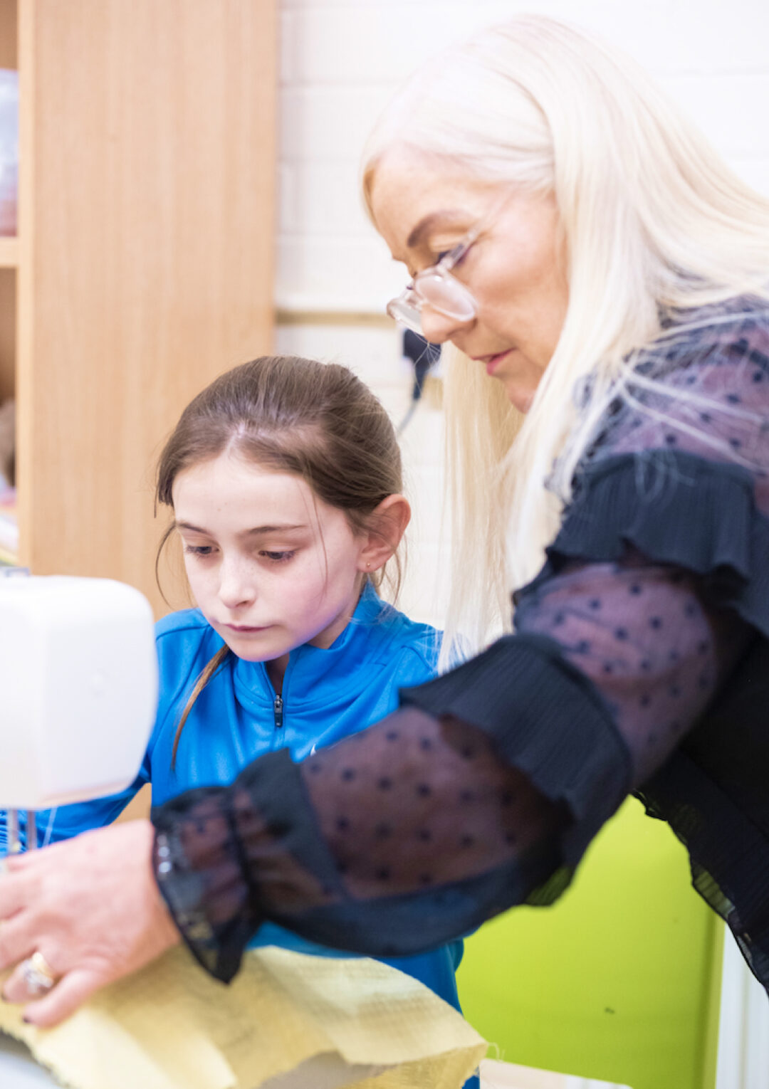 A young member of The Bronte Youth Club being taught how to sew from a member of staff at The Bronte Youth and Community Centre based in Liverpool City Centre