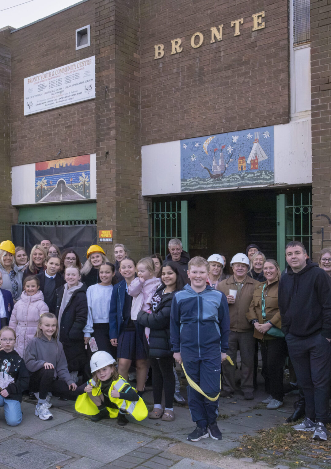 Group photo of staff, young people, community members and our contractors from Truline stood outside The Bronte Youth and Community Centre building at our groundbreaking event, celebrating the beginning of The Bronte Big Build renovation project. Posed at the front entrance of the building on Trowbridge Street near the Bullring in Liverpool City Centre