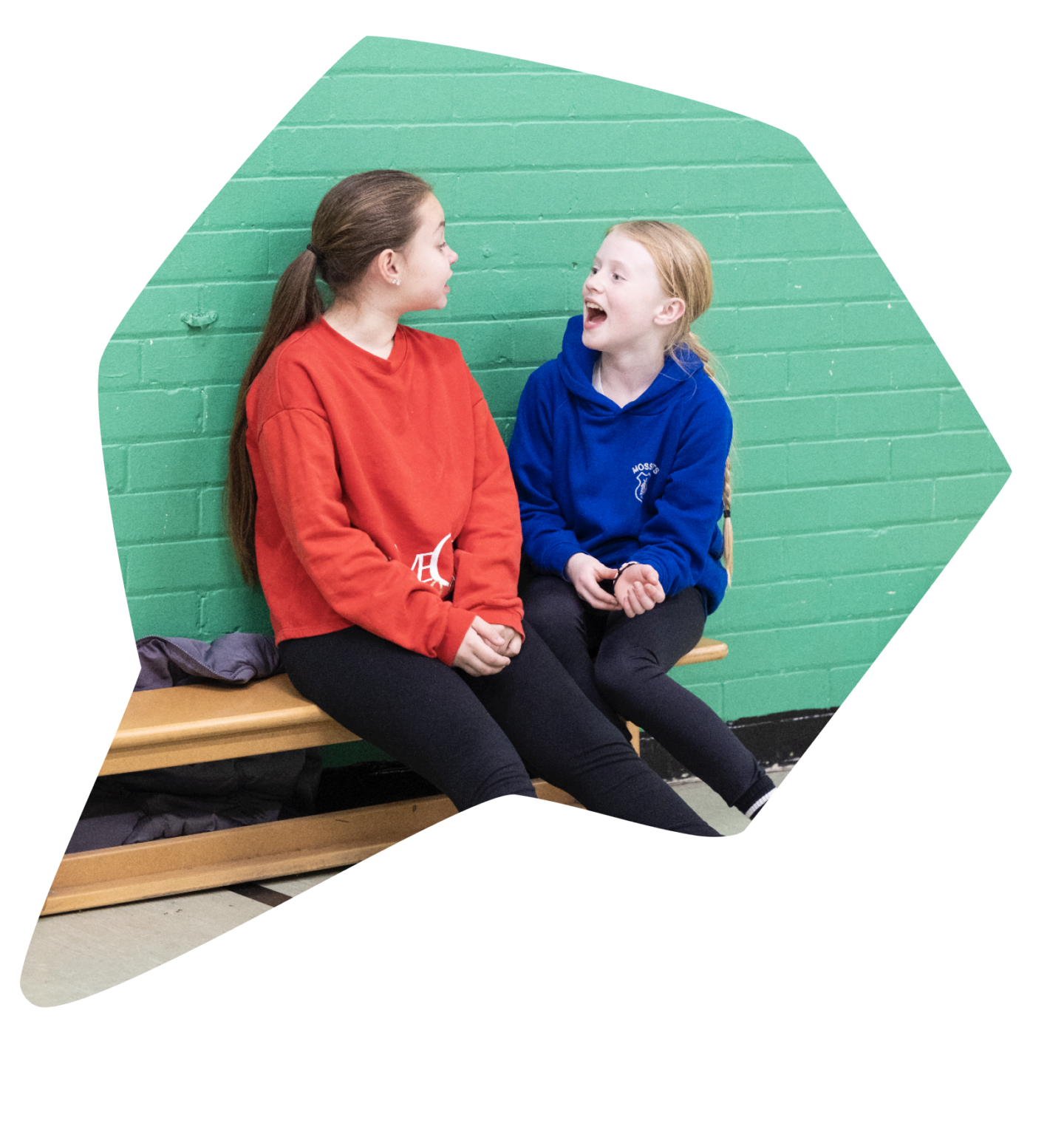 Two young people talking on a bench in the sports hall at The Bronte Youth and Community Centre in Liverpool City Centre